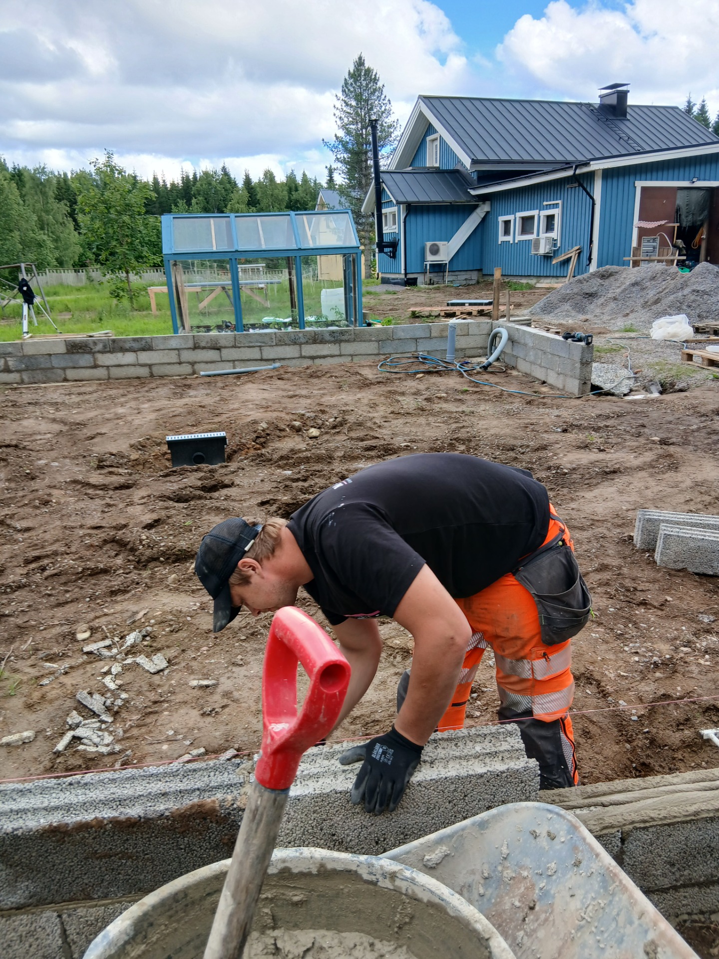 Hymyilevä tarjoilija laskee kädessään kylttiä “WE’RE OPEN” baarin taustalla, lasivalot ja hyllyt näkyvät.